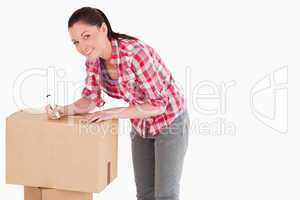 Beautiful woman writing on cardboard boxes with a marker while s