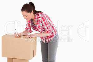 Attractive woman writing on cardboard boxes with a marker while