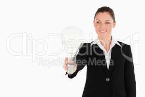 Charming woman in suit holding a light bulb while standing