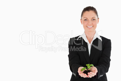 Good looking woman in suit holding a small plant