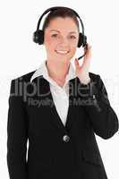 Portrait of a good looking woman in suit using headphones and po