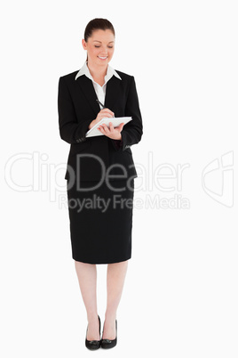 Beautiful woman in suit writing on a notebook
