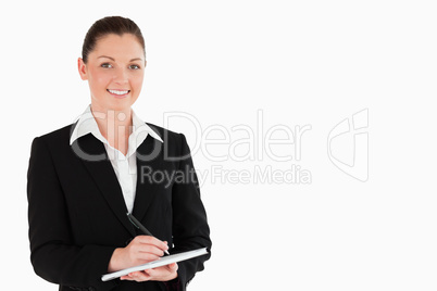 Portrait of a good looking woman in suit writing on a notebook