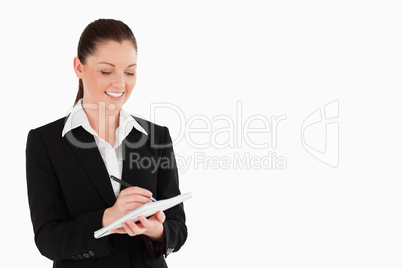 Portrait of a charming woman in suit writing on a notebook