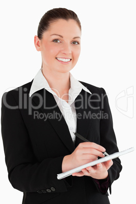 Portrait of a cute woman in suit writing on a notebook