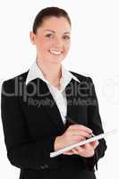 Portrait of a cute woman in suit writing on a notebook