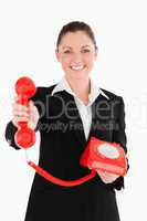 Good looking woman in suit holding a red telephone