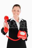Attractive woman in suit holding a red telephone