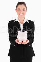 Attractive woman in suit holding a pink piggy bank