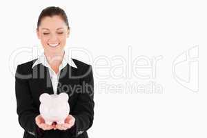Gorgeous woman in suit holding a pink piggy bank