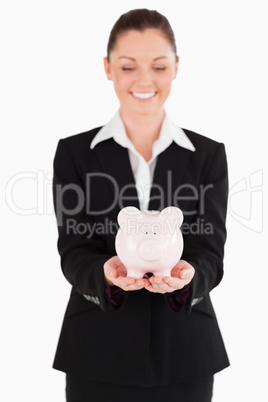 Good looking woman in suit holding a pink piggy bank