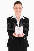 Good looking woman in suit holding a pink piggy bank