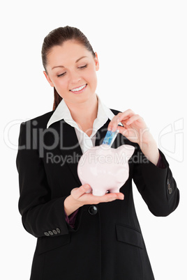 Beautiful woman in suit inserting a money bill in a pink piggy b