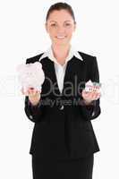 Good looking woman in suit holding a piggy bank and a miniature