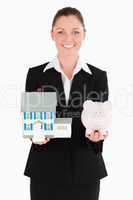 Charming woman in suit holding a piggy bank and a miniature hous
