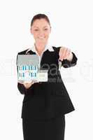 Beautiful woman in suit holding keys and a miniature house