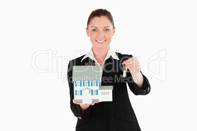 Good looking woman in suit holding keys and a miniature house