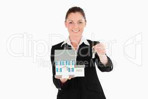 Good looking woman in suit holding keys and a miniature house