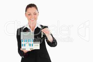 Charming woman in suit holding keys and a miniature house
