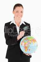 Attractive female in suit holding a globe and using a magnifying