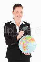 Beautiful female in suit holding a globe and using a magnifying