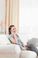 Charming woman on the phone while sitting on a sofa