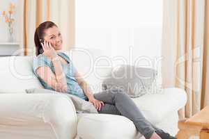 Beautiful woman on the phone while sitting on a sofa