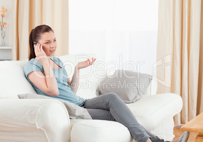 Upset woman on the phone while sitting on a sofa