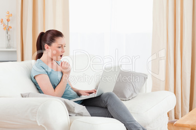 Surprised woman gambling with her computer while sitting on a so