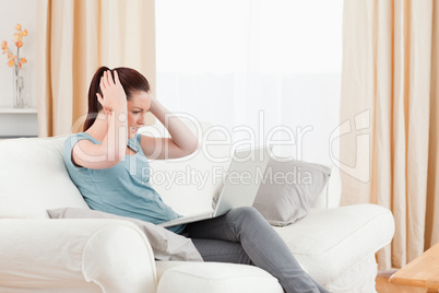 Upset woman gambling with her computer while sitting on a sofa