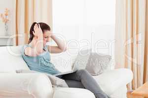 Upset woman gambling with her computer while sitting on a sofa