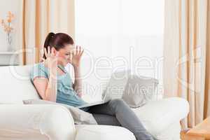 Angry woman gambling with her computer while sitting on a sofa