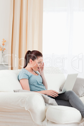 Pretty woman relaxing with her laptop while sitting on a sofa