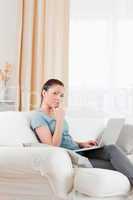 Sad woman relaxing with her laptop while sitting on a sofa