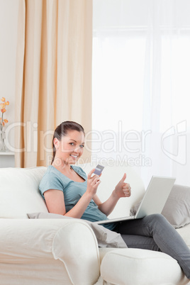 Gorgeous woman making an online payment with her credit card whi