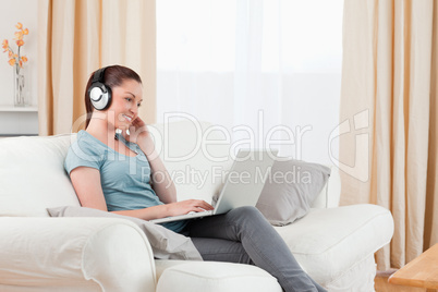 Attractive woman with headphones relaxing with her laptop while