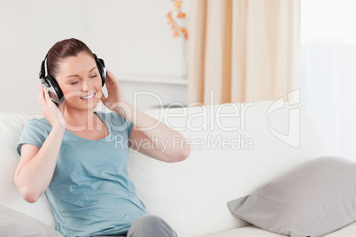 Charming woman relaxing with headphones while sitting on a sofa