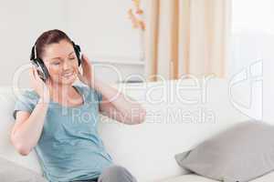 Charming woman relaxing with headphones while sitting on a sofa