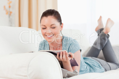 Lovely woman reading a magazine while lying on a sofa