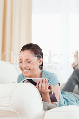 Beautiful woman reading a magazine while lying on a sofa