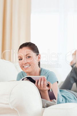 Attractive woman reading a magazine while lying on a sofa