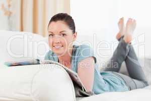 Good looking woman reading a magazine while lying on a sofa