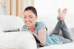 Charming woman reading a magazine while lying on a sofa