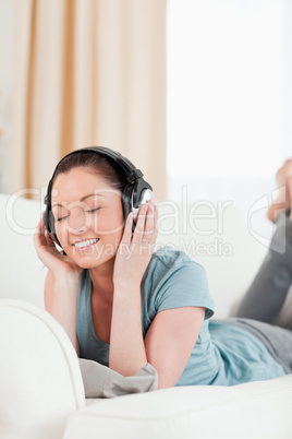 Beautiful woman with headphones posing while lying on a sofa