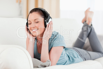 Good looking woman with headphones posing while lying on a sofa