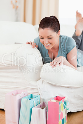 Charming woman looking at her shopping bags while lying on a sof