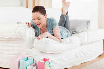 Beautiful woman looking at her shopping bags while lying on a so