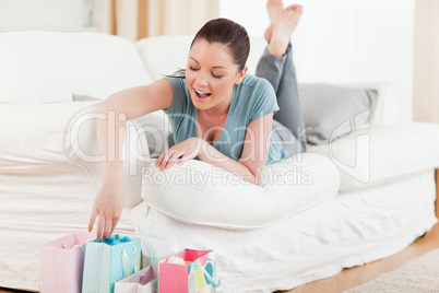 Beautiful woman touching her shopping bags while lying on a sofa