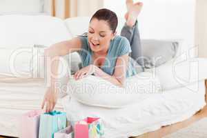 Beautiful woman touching her shopping bags while lying on a sofa