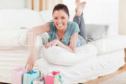 Good looking woman touching her shopping bags while lying on a s